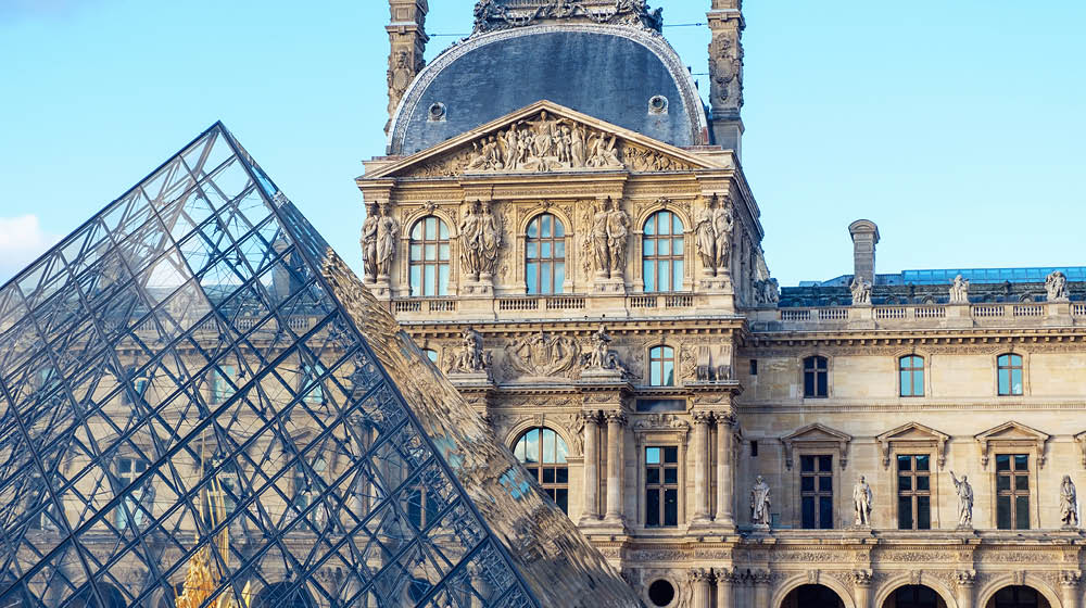 Louvre museum in orange and teal. Close up shot to a touristic atraction in Paris, France. No refelctions on the pyramid. Blueish tone on the building
