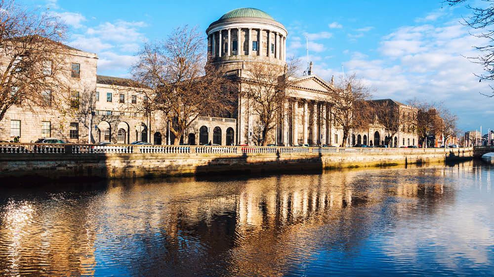 Dublin, Ireland. Four courts building in Dublin, Ireland with reflection in river Liffey during the sunny evening. cloudy blue sky
