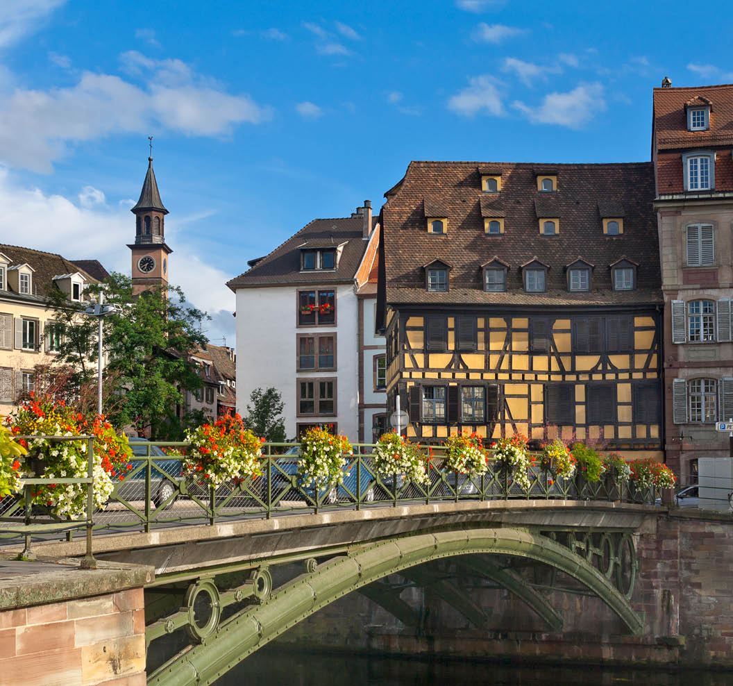 Picturesque street with historical houses in Strasbourg, France seen across bridge