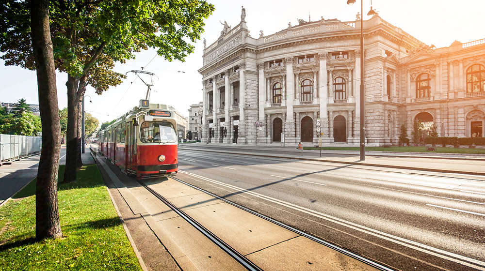 Beautiful view of famous Wiener Ringstrasse with historic Burgtheater (Imperial Court Theatre) and traditional red electric tram at sunset in Vienna, Austria