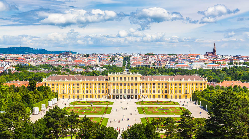 Classic view of famous Schonbrunn Palace with scenic Great Parterre garden on a beautiful sunny day with blue sky and clouds in summer, Vienna, Austria
