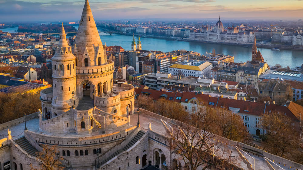 Budapest, Hungary - The main tower of the famous Fisherman's Bastion (Halaszbastya) from above with Parliament building and River Danube at background on a sunny morning