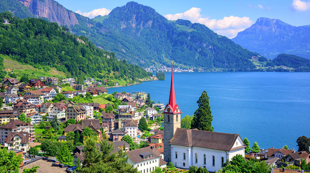 Little swiss town with gothic church on Lake Lucerne and Alps mountain, Switzerland