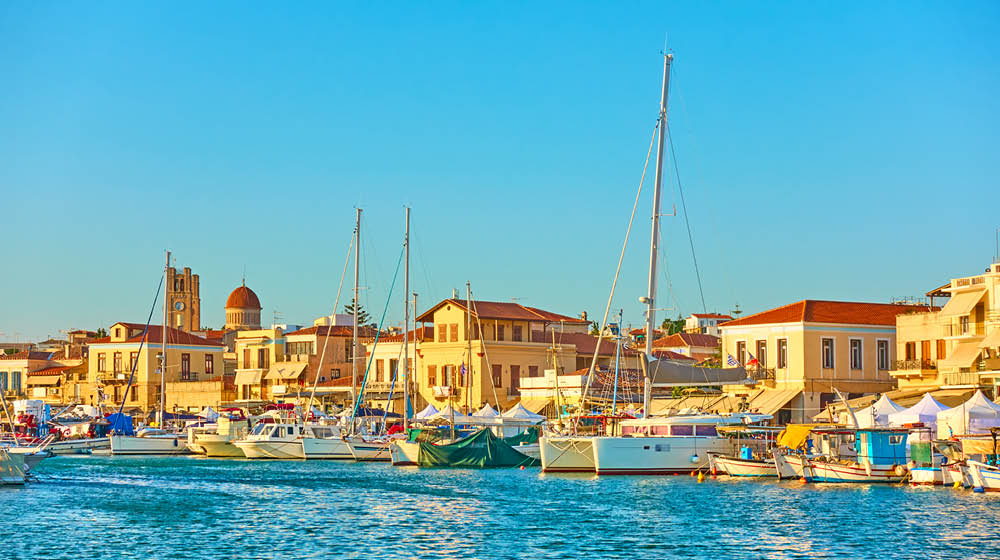 Yachts and boats in the harbour and waterfront in Aegina town at sunset, Aegina Island, Greece