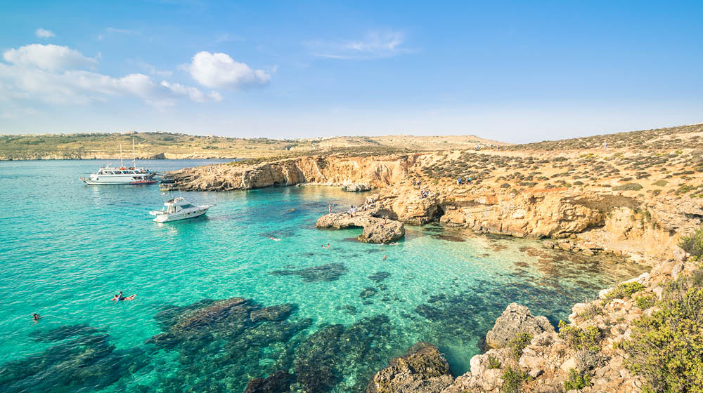 The world famous Blue Lagoon in Comino island - Mediterranean nature wonder in the beautiful Malta - Unrecognizable international tourist people and snorkeling divers - Exclusive travel destinations