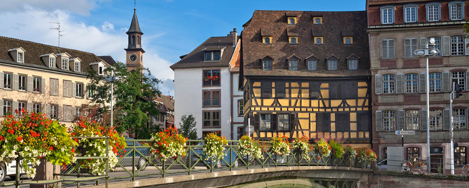 Picturesque street with historical houses in Strasbourg, France seen across bridge