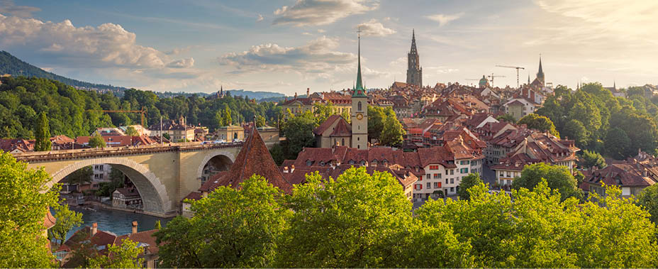 View of the city of Bern on a summer evening. On the left is the Nydeggbr cke (bridge), and the towers belong to the Nydeggkirche (church) and Berner M nster (Cathedral of Bern).