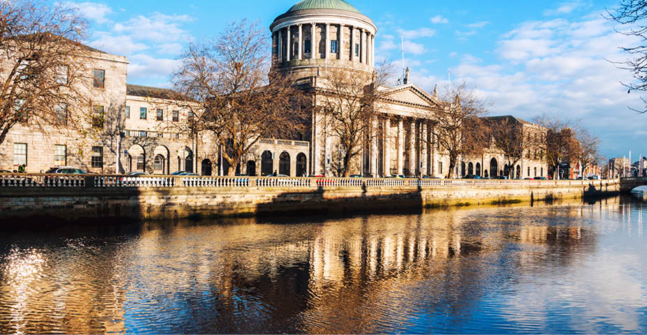 Dublin, Ireland. Four courts building in Dublin, Ireland with reflection in river Liffey during the sunny evening. cloudy blue sky