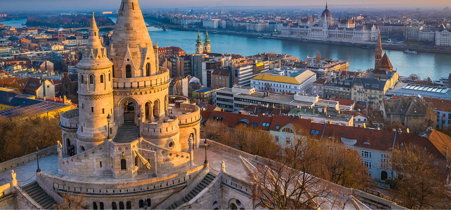 Budapest, Hungary - The main tower of the famous Fisherman's Bastion (Halaszbastya) from above with Parliament building and River Danube at background on a sunny morning